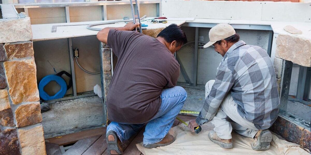 two contractors finishing an outdoor kitchen with natural stone veneer