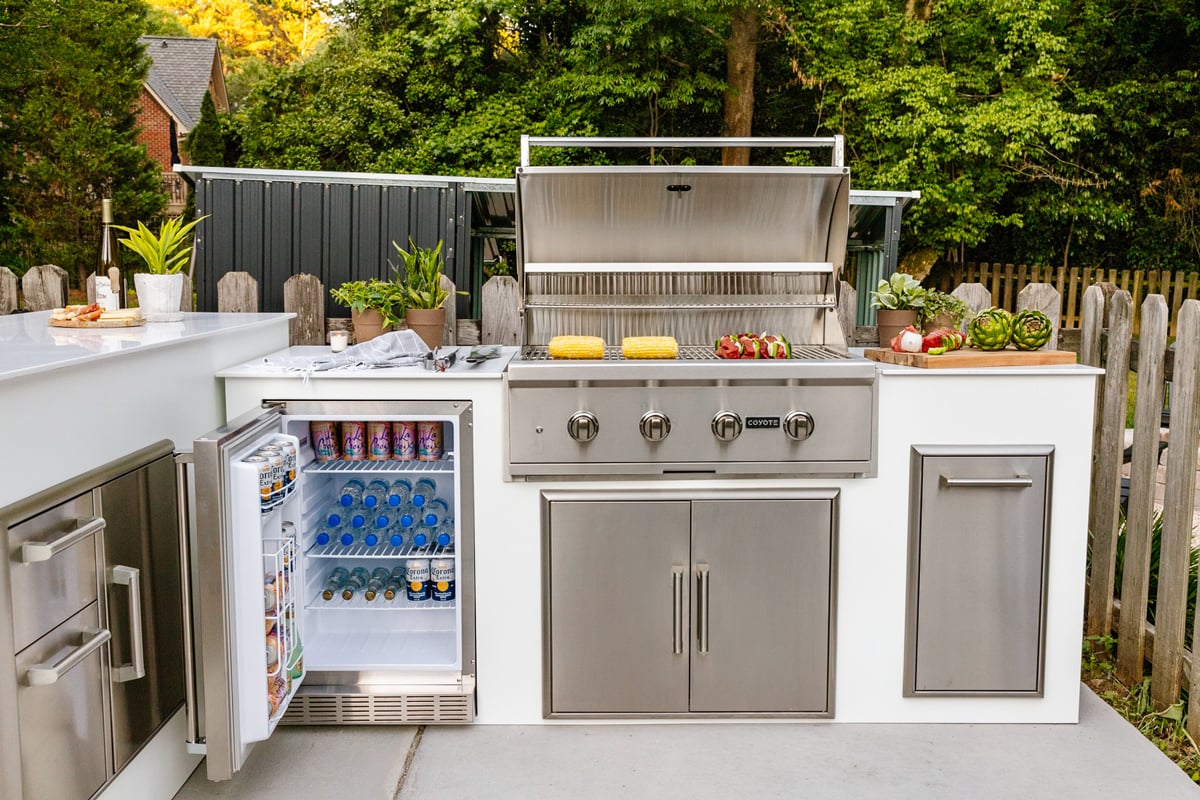 white grill island with open grill hood and refrigerator