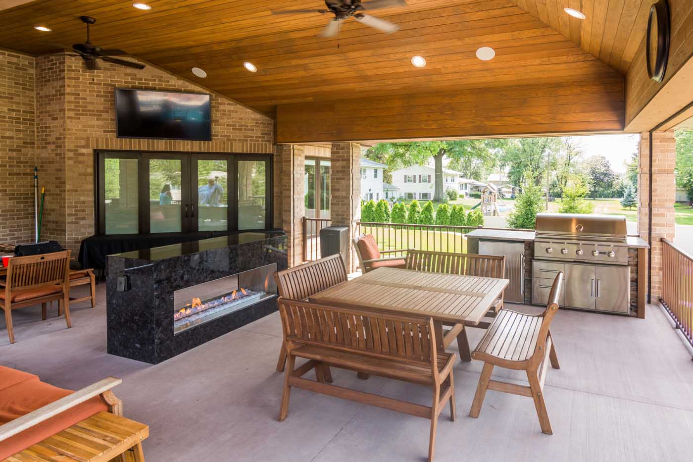 an rta summer kitchen under a covered patio with a fireplace