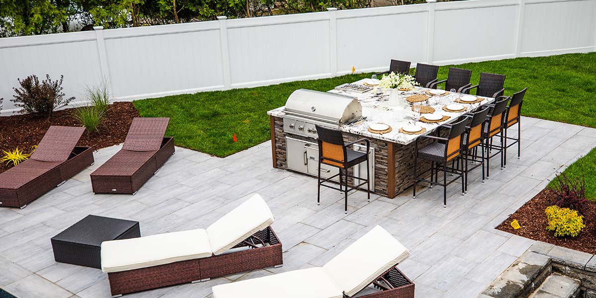 backyard patio with lounge chairs and large square style outdoor kitchen