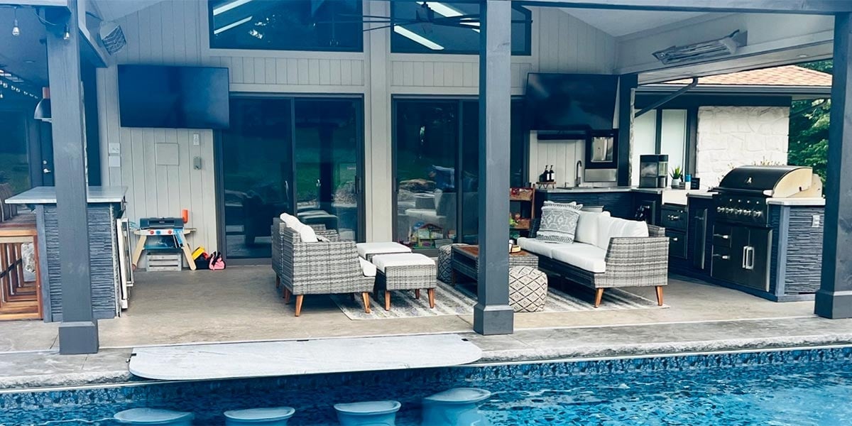 backyard pool area with covered patio seating area and outdoor kitchen