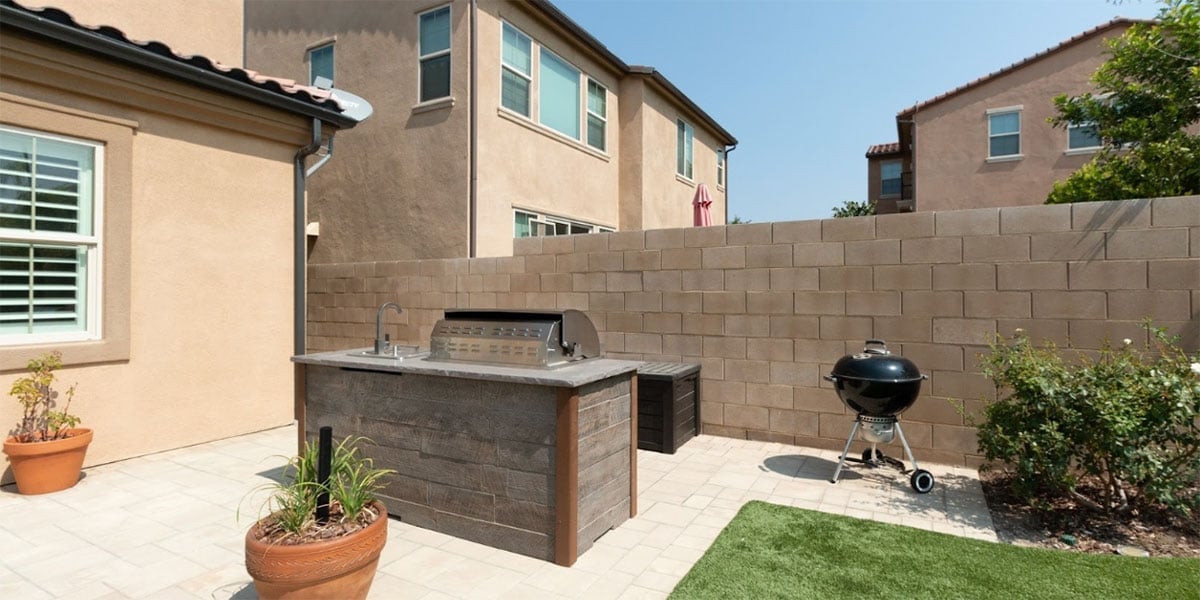 backyard with outdoor kitchen weber kettle grill and planters on patio