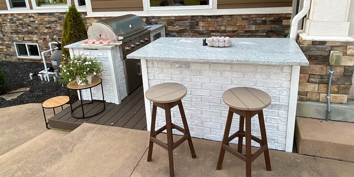bar island with stool and patio next to house in reclaimed brick white