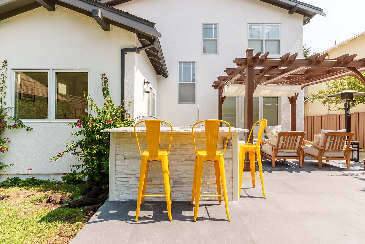 bar seating with sink at a small outdoor kitchen with bright yellow stools
