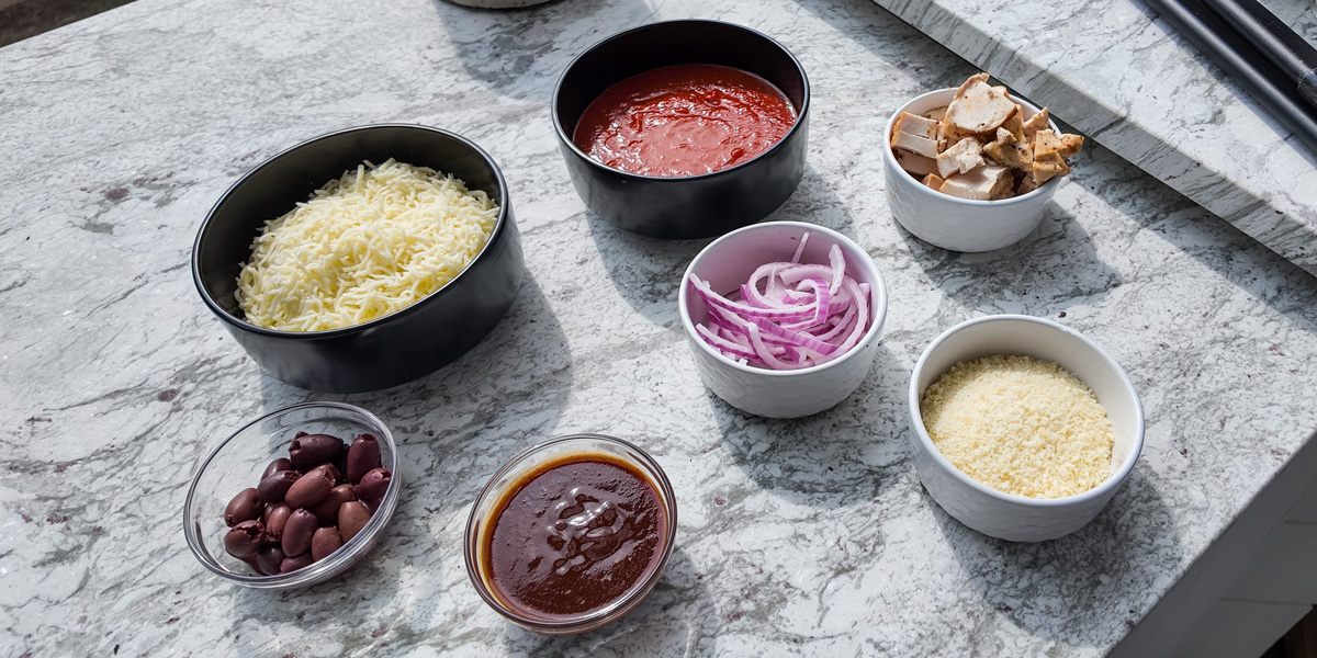 bowls of pizza toppings on granite countertop