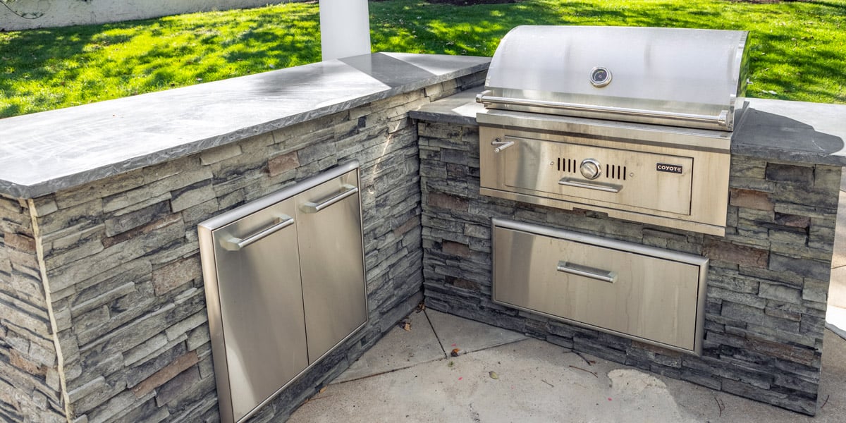 built in charcoal grill model in stacked stone outdoor kitchen