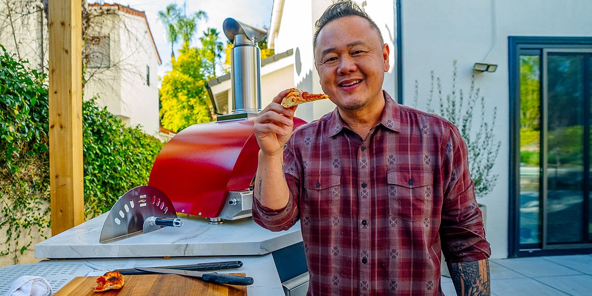 Chef Jet Tila eating pizza at his outdoor kitchen