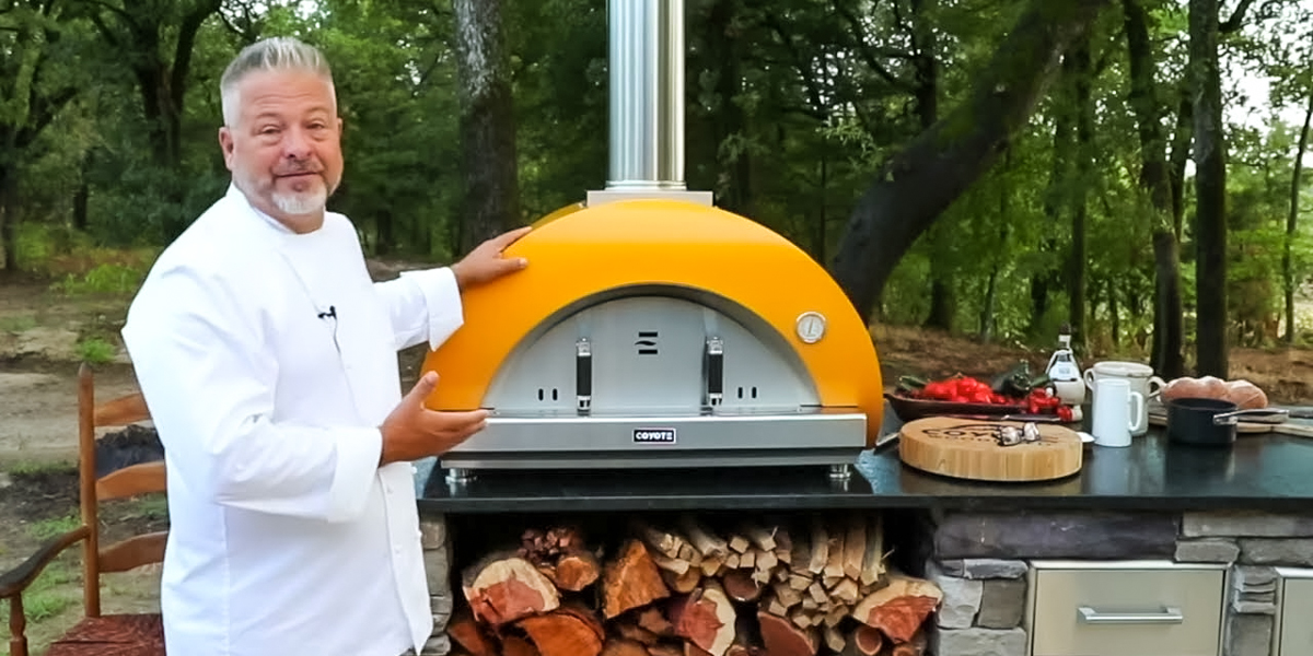 chef standing next to large pizza oven