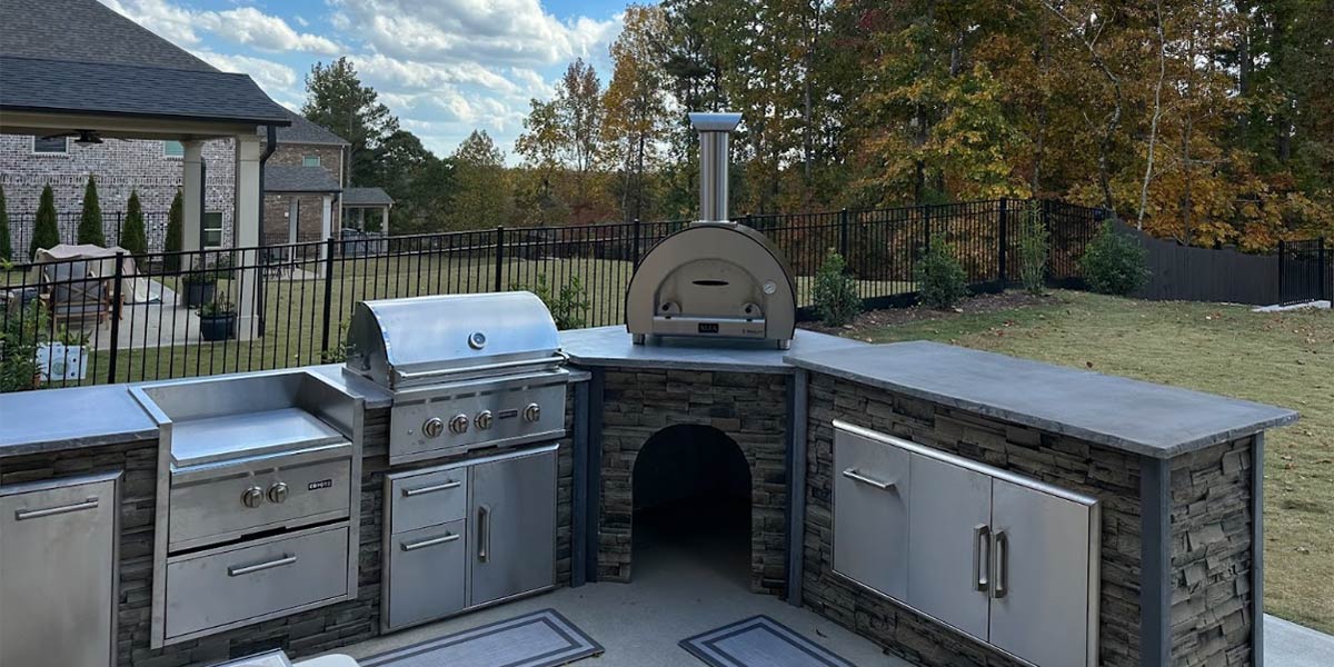 close up of stone outdoor kitchen with pizza oven overlooking fall foliage