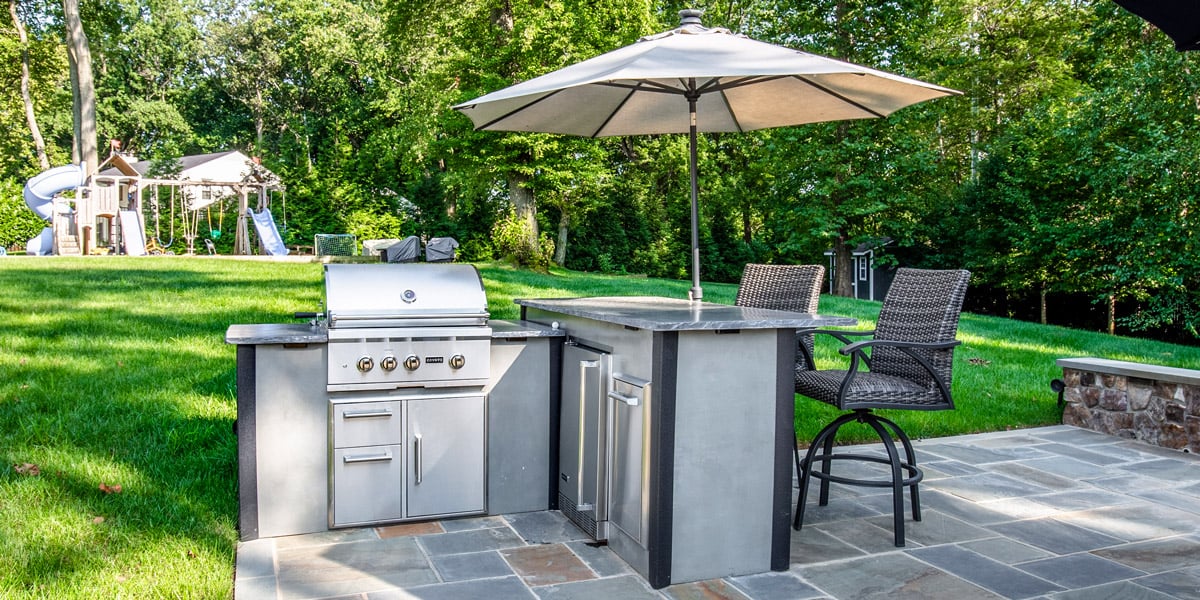 compact outdoor kitchen with storage drawers and fridge bar seating and umbrella