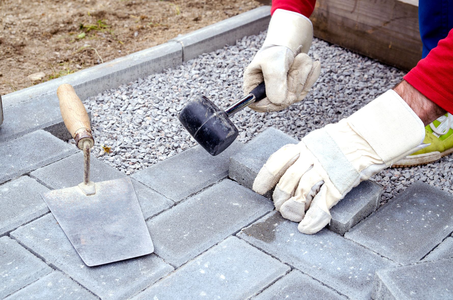 contractor laying paver patio surface for outdoor kitchen