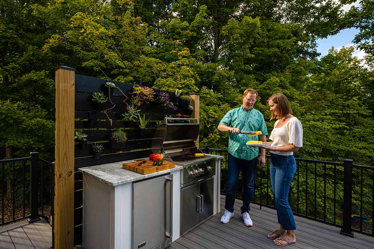 Couple plating food next to outdoor kitchen