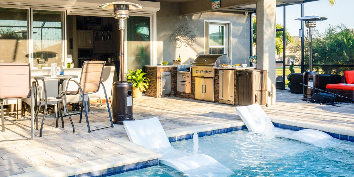 covered outdoor kitchen design with lounge area and pool