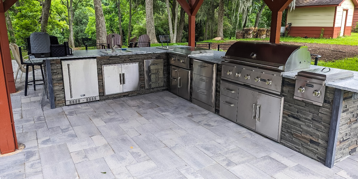 covered outdoor l shaped kitchen idea with large gas grill and side burner
