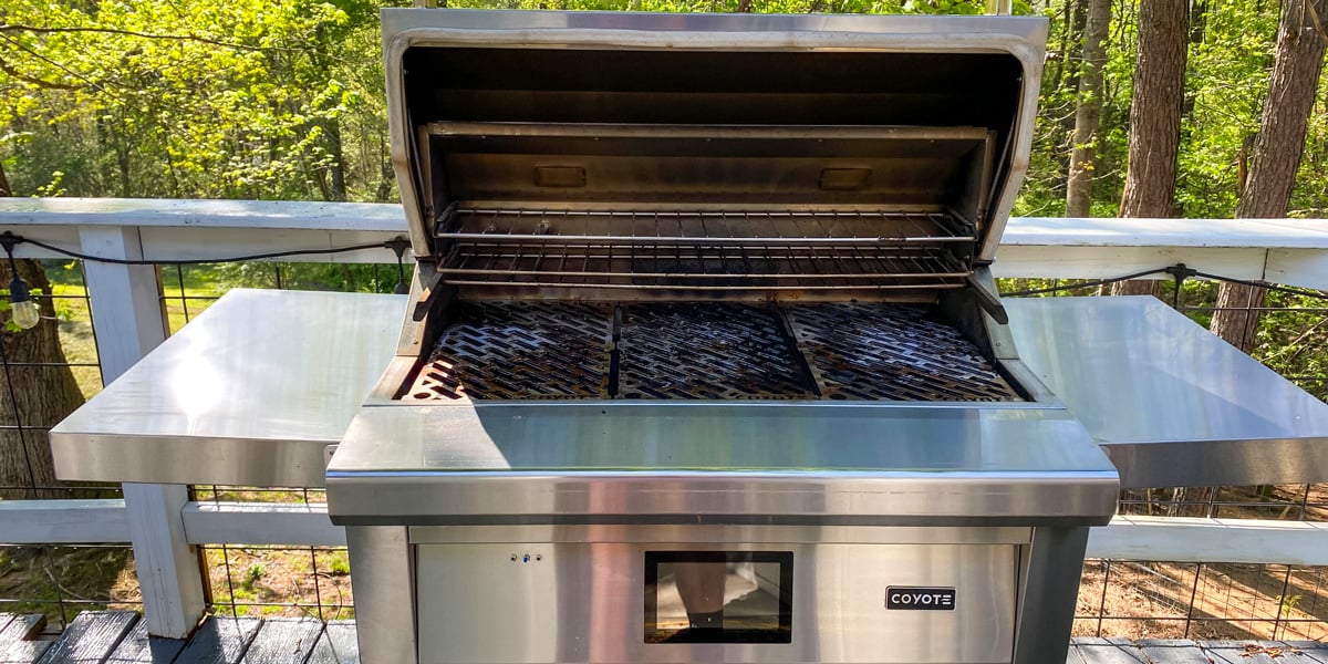 coyote pellet smoker with hood opened on deck