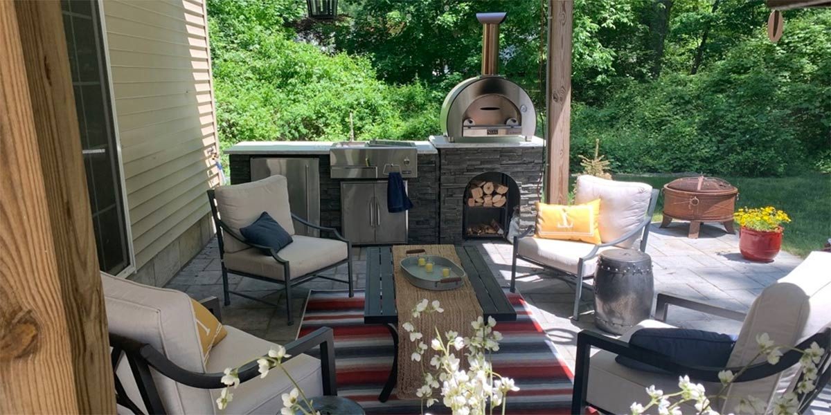 Linear island with pizza oven and refreshment center by outdoor seating.