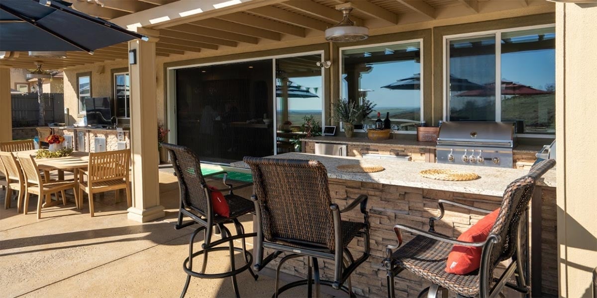 extended backyard patio with outdoor kitchen and dining table