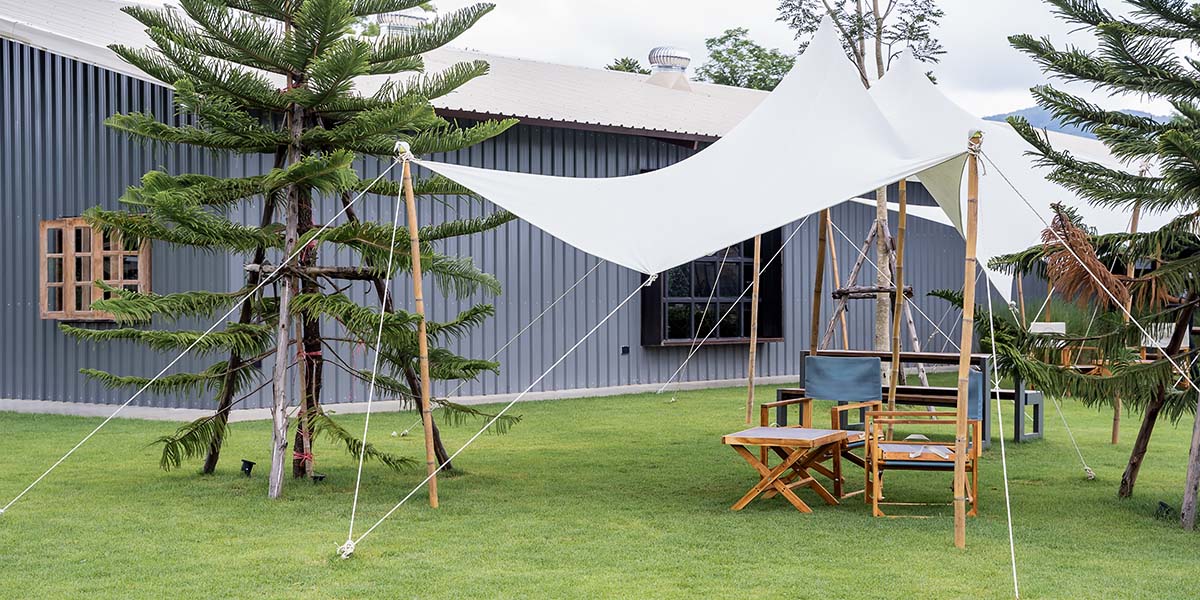 fabric canopy with wood poles in the backyard with chairs