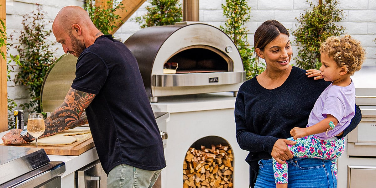 family cooking a meal outside at outdoor kitchen