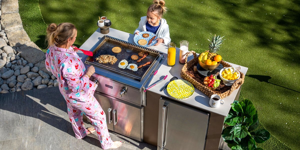 family cooking breakfast outside with outdoor kitchen