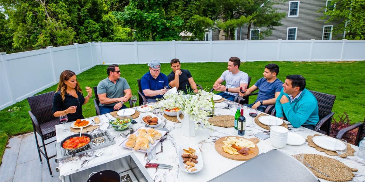 family enjoying meal outside at outdoor kitchen