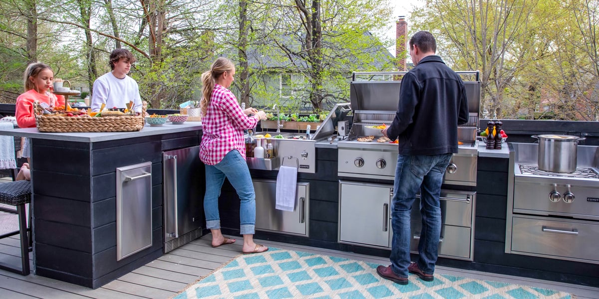family enjoying outdoor kitchen and cooking outside