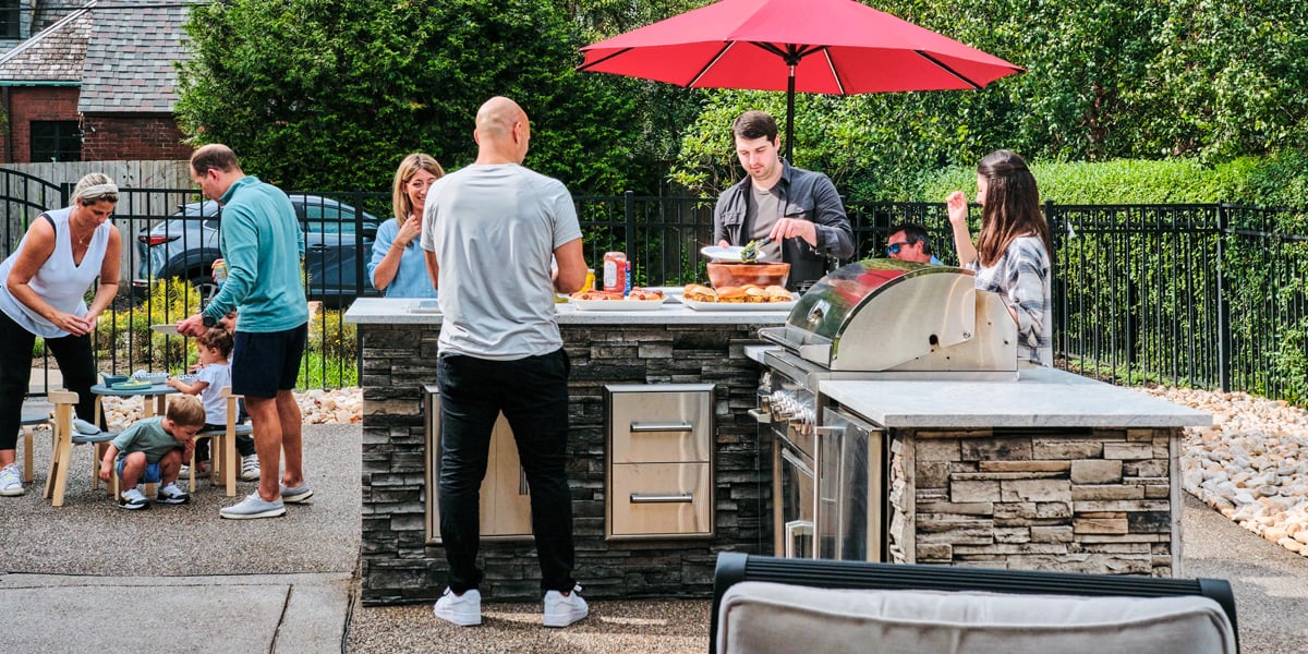 family grilling and enjoying a meal at an outdoor kitchen