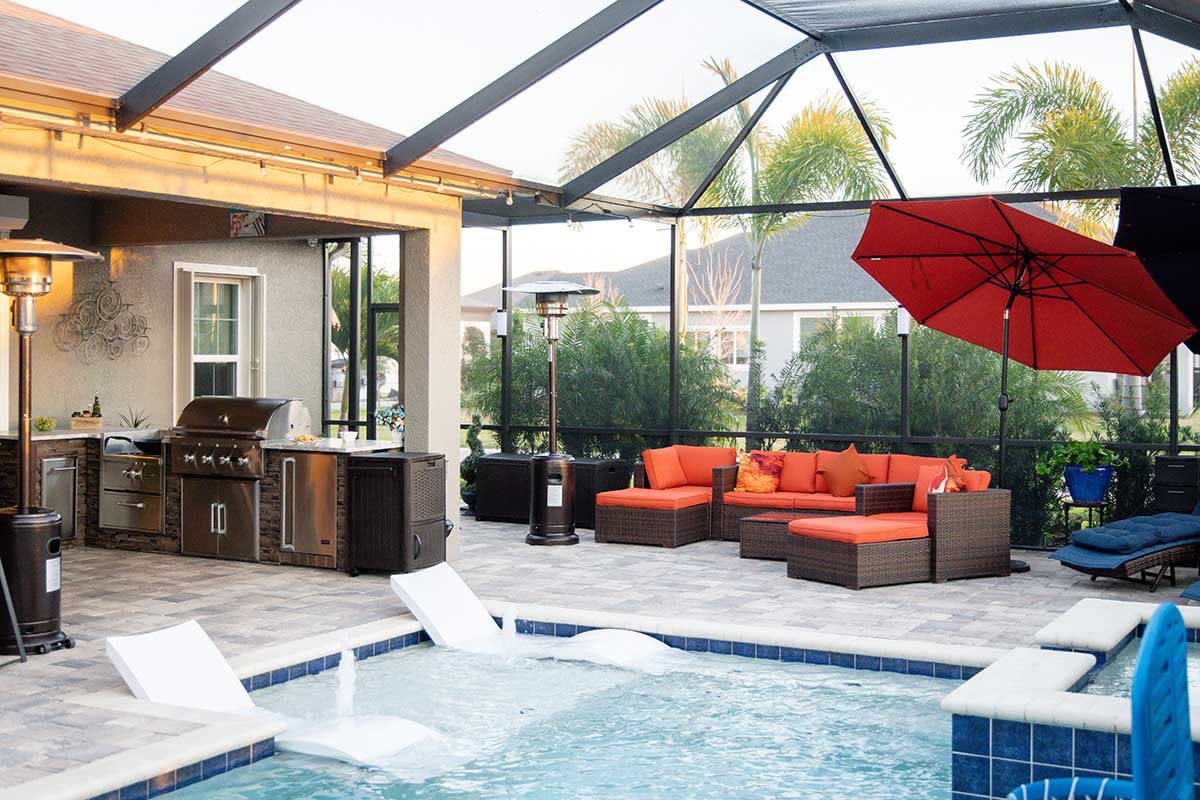 florida room furniture next to a pool and l shaped outdoor kitchen