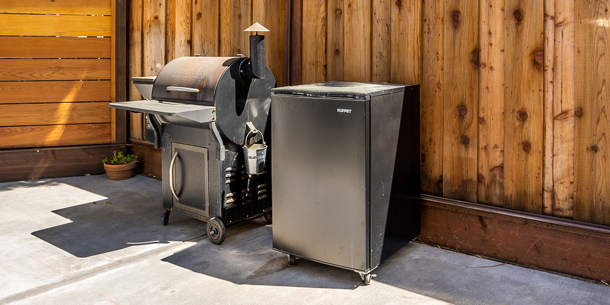 freestanding outdoor refrigerator next to grill cart