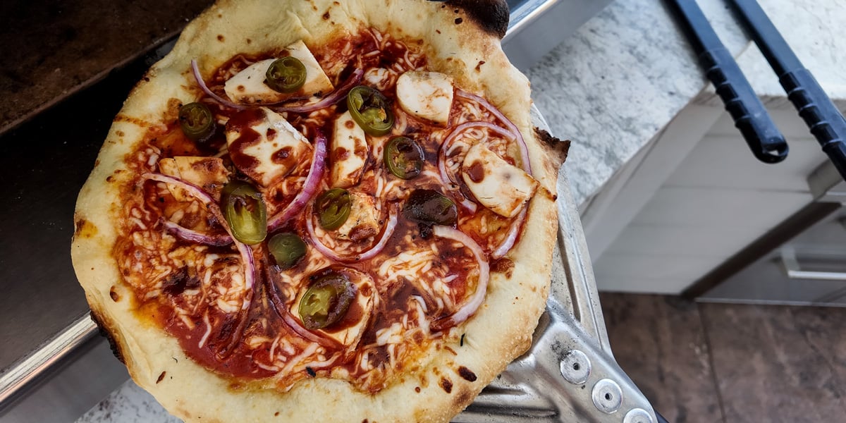 fresh baked pizza being removed from pizza oven