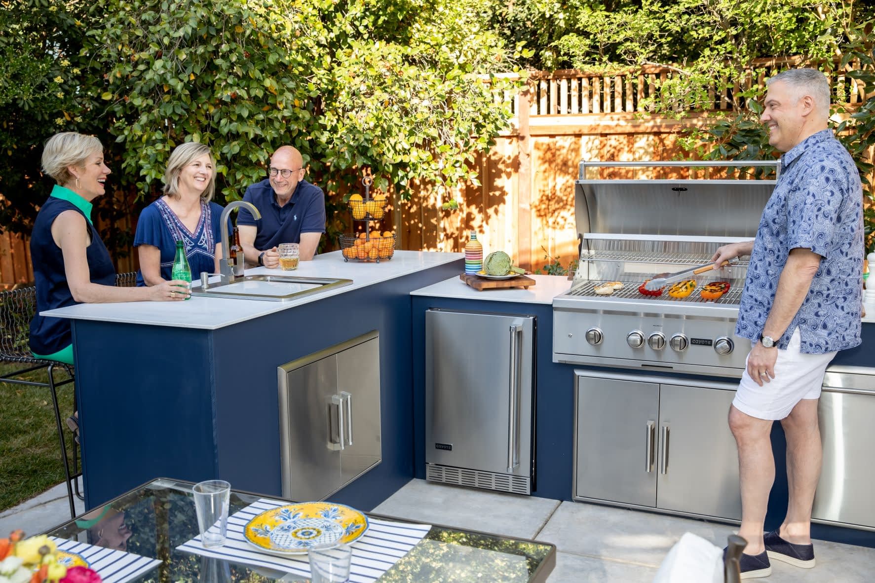 Friends and Family Enjoying an RTA MOKS Modular Outdoor Kitchen with someone cooking dinner on the grill