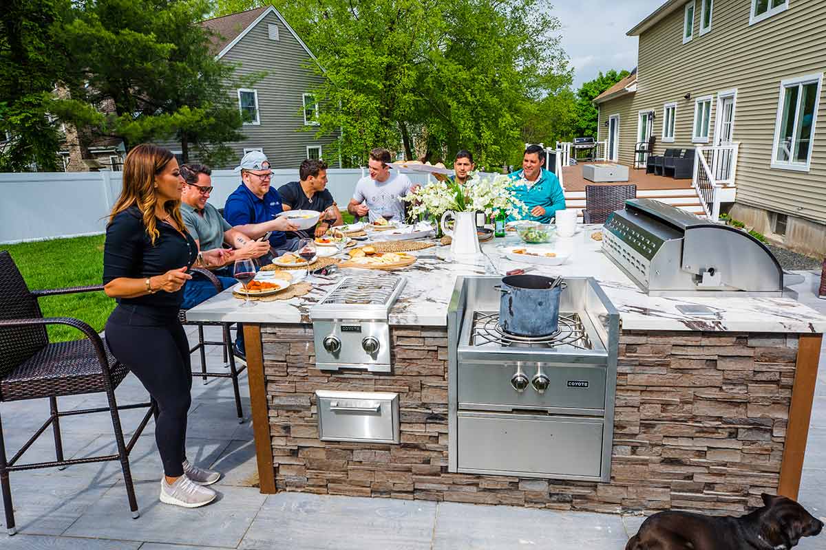 friends gathering at outdoor kitchen to eat dinner