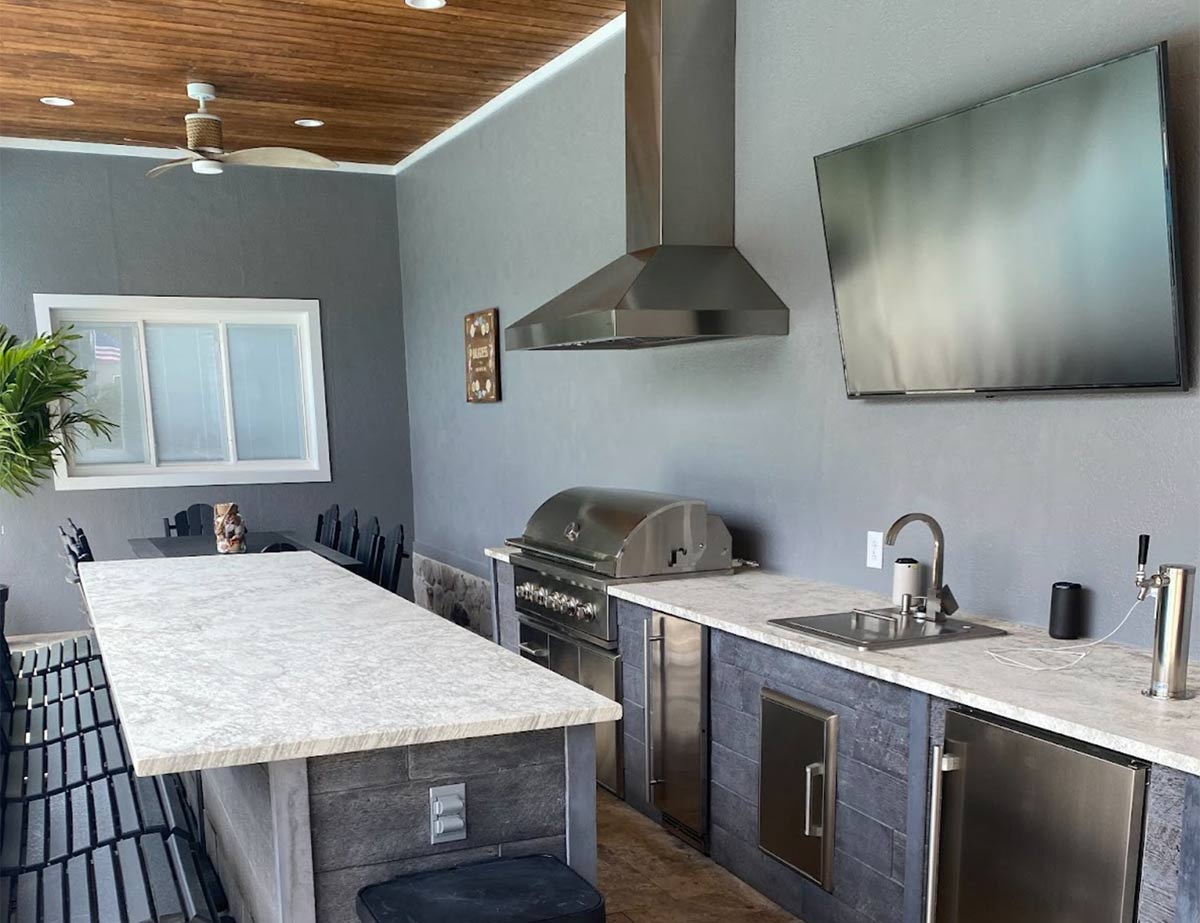 galley outdoor kitchen with bar seating and a tv