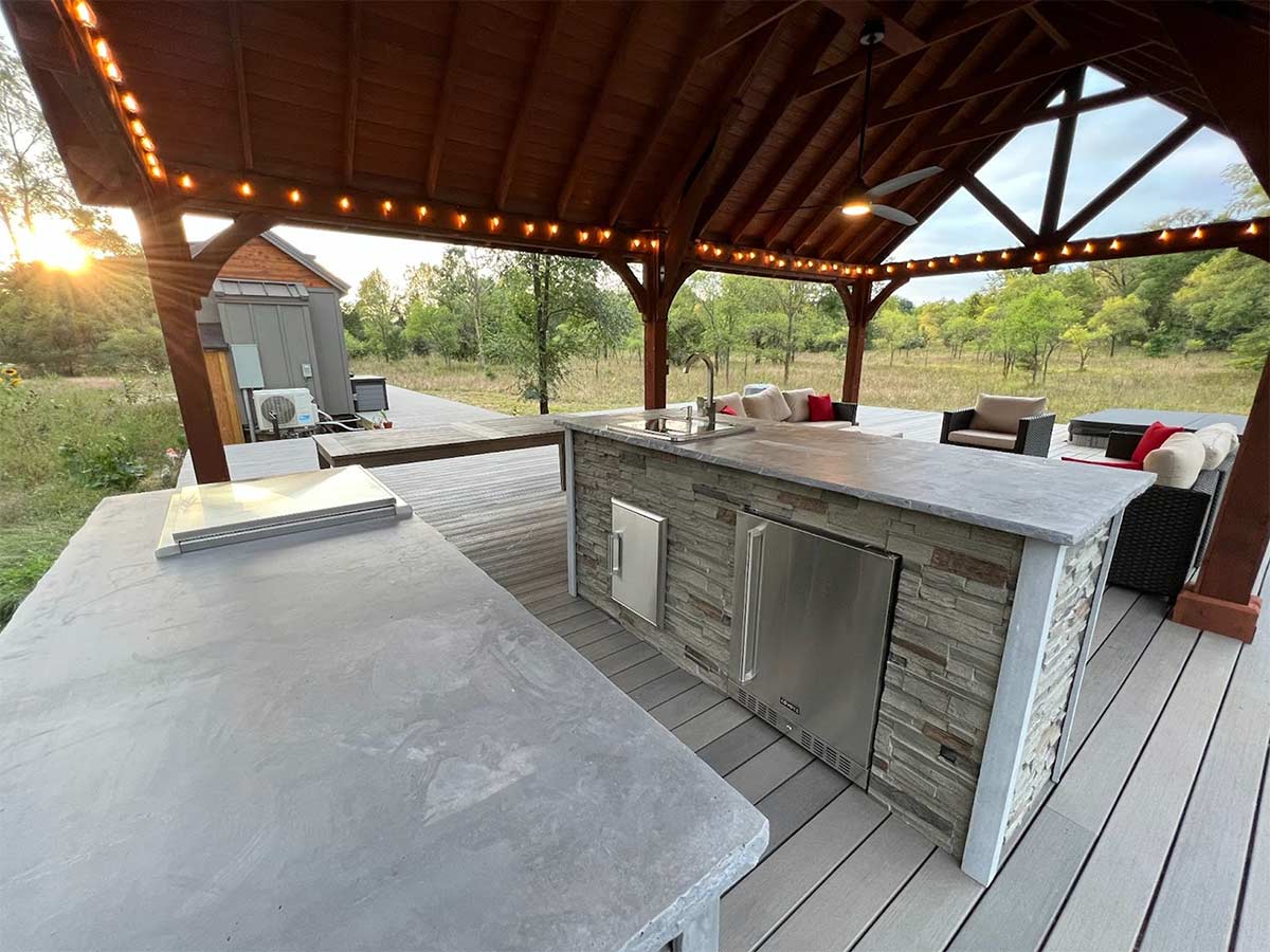 galley style outdoor kitchen under outdoor pavilion with bar lighting