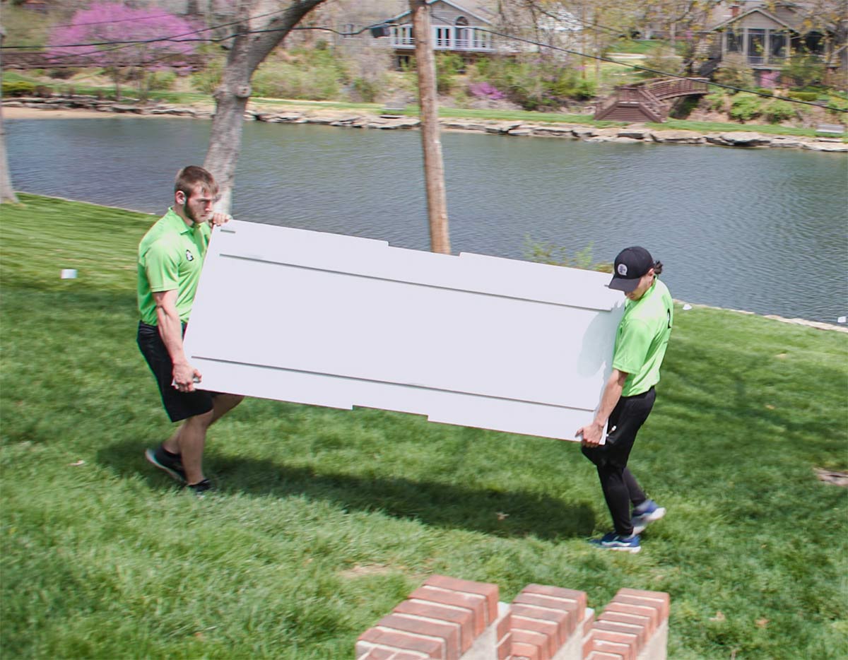 two men carrying an rta panel to the patio for installation