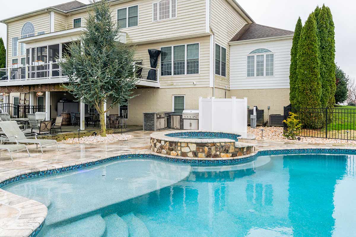 l shaped outdoor kitchen by hot tub on patio