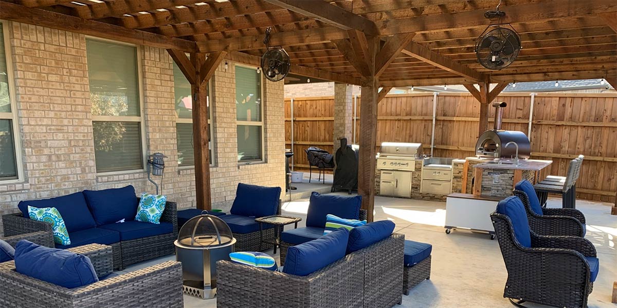 l shaped outdoor kitchen in texas next to outdoor seating with a pergola
