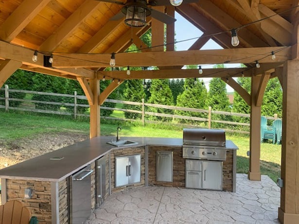 l shaped outdoor kitchen under gondola on patio with refrigerator and storage in stacked stone terra finish