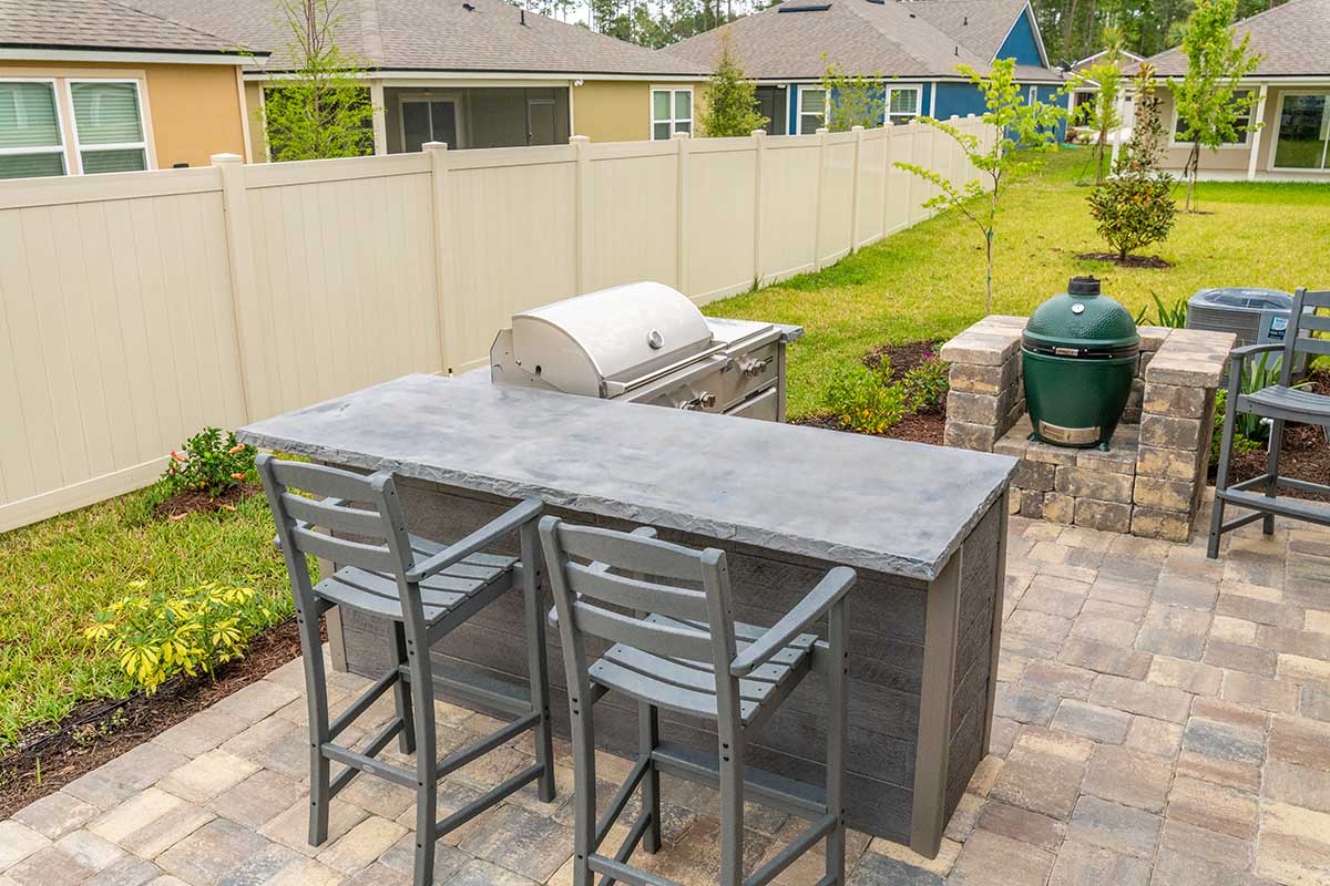 l shaped outdoor kitchen with bar seating on patio with standalone green egg