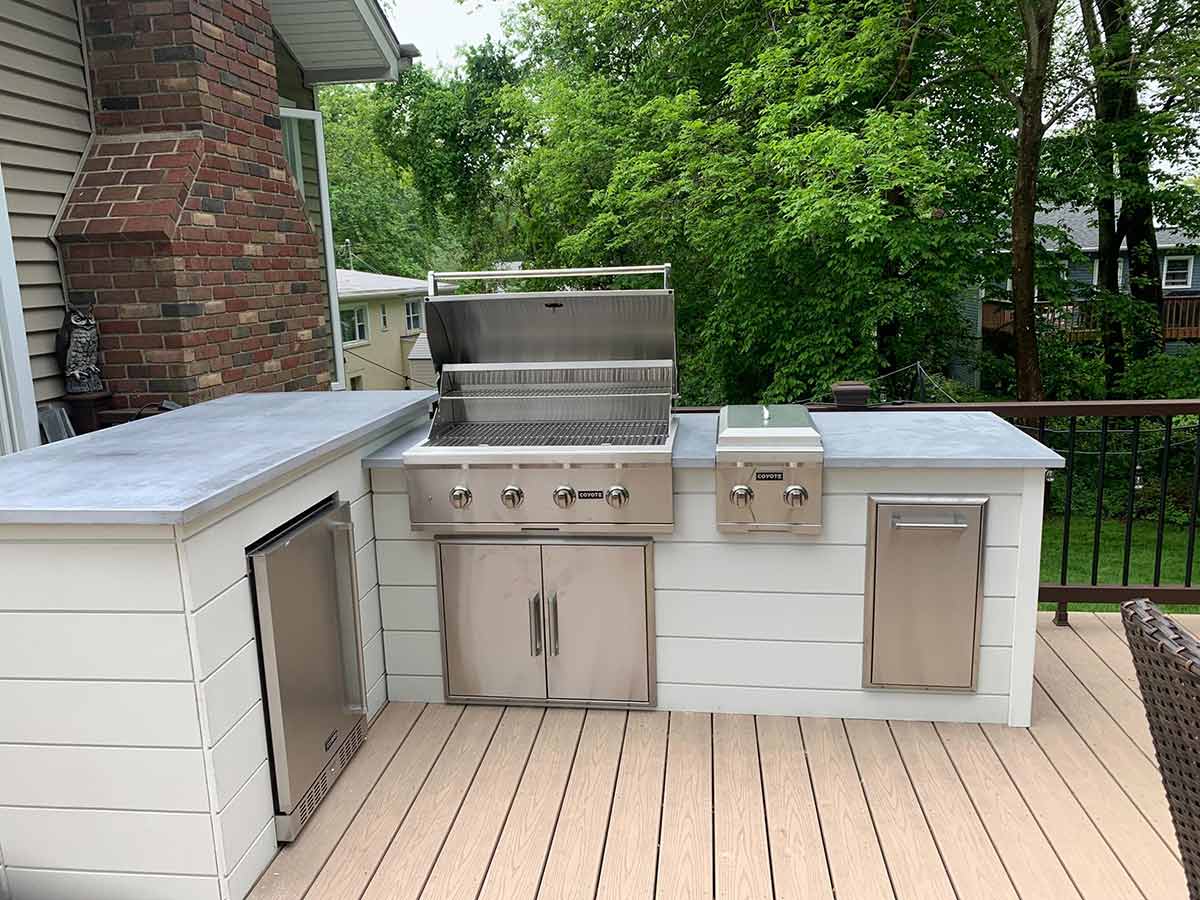 l shaped outdoor kitchen with open grill side burner and refrigerator on a deck