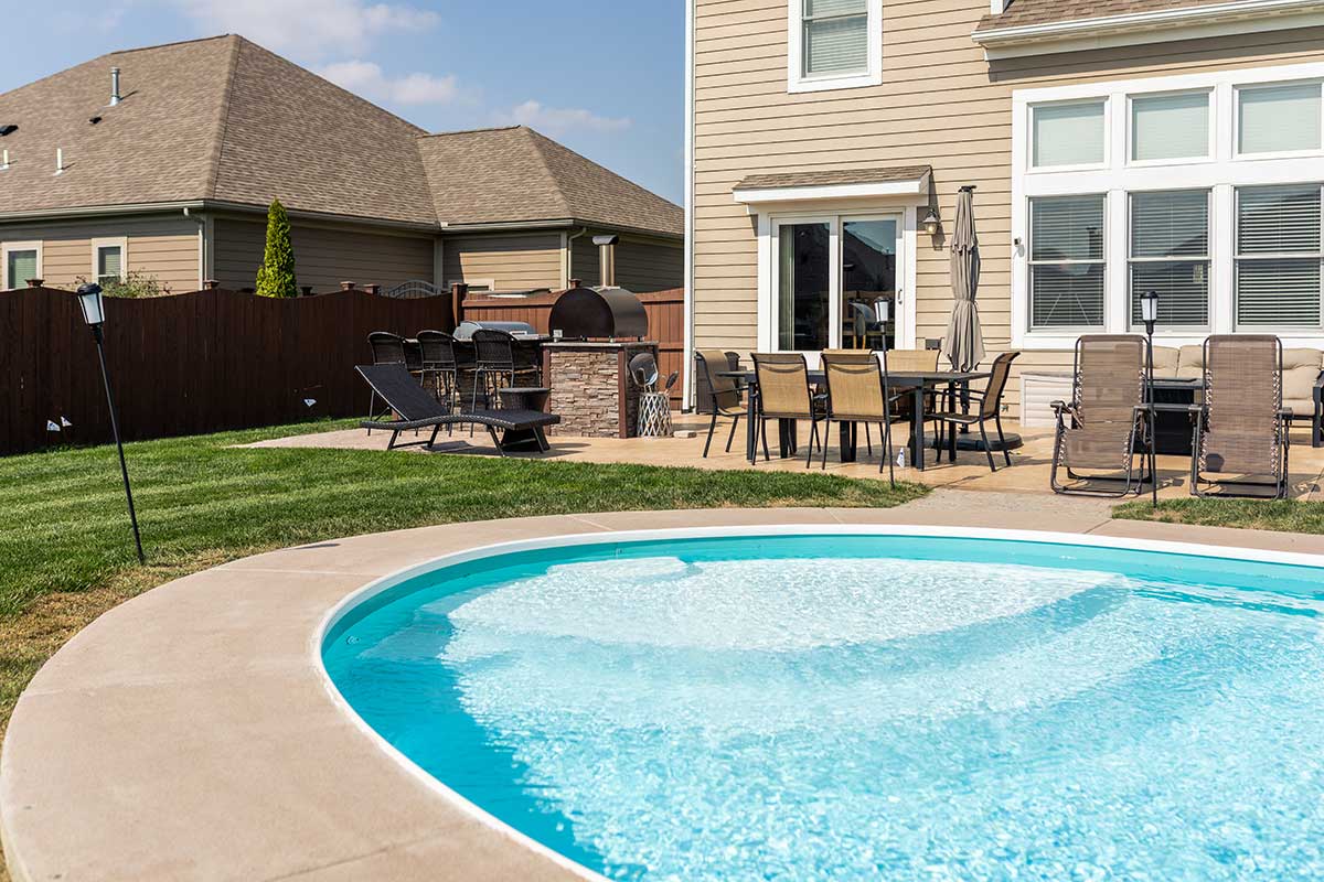 l shaped outdoor kitchen with pizza oven by pool