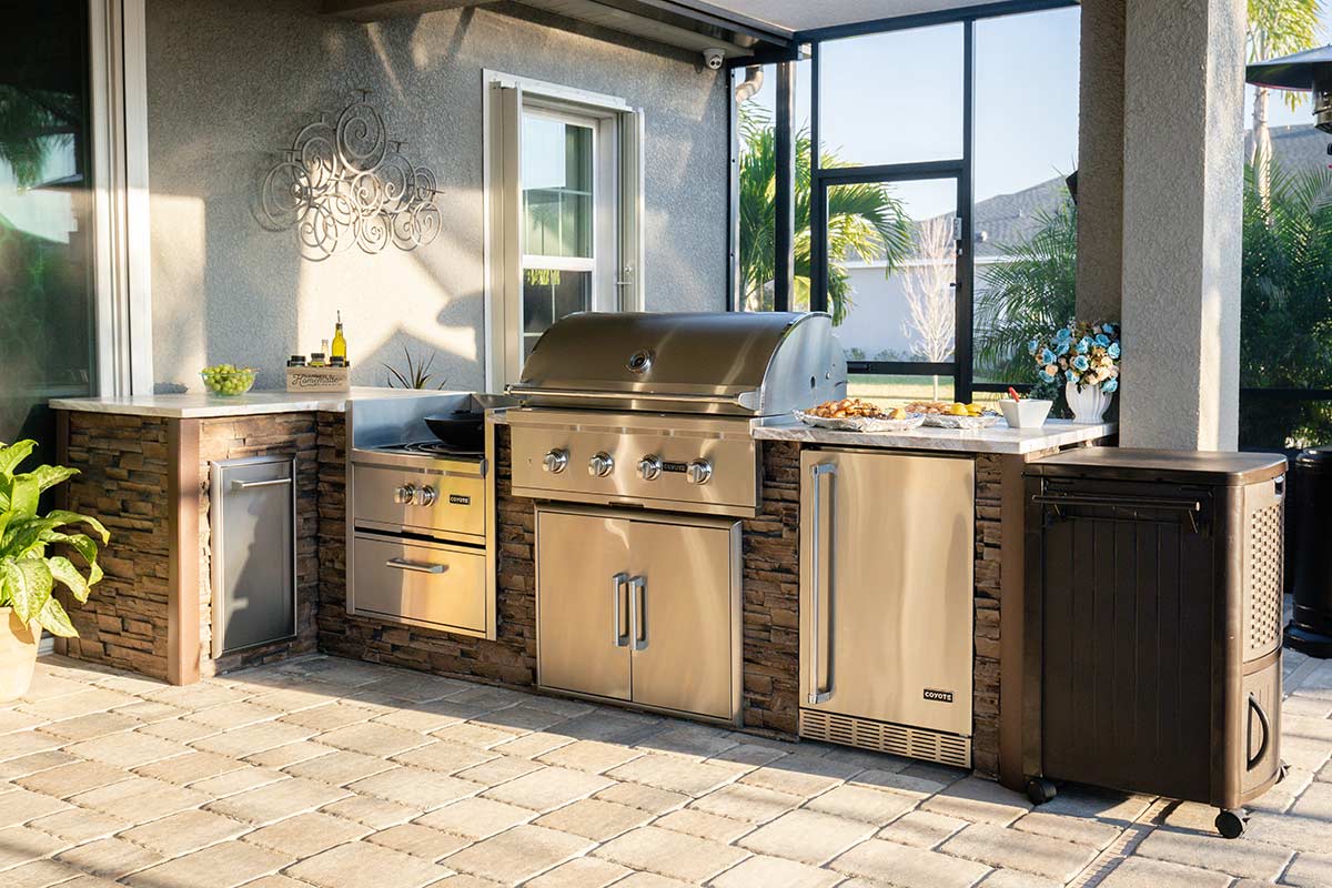 l shaped outdoor kitchen with power burner and refrigerator in a florida room