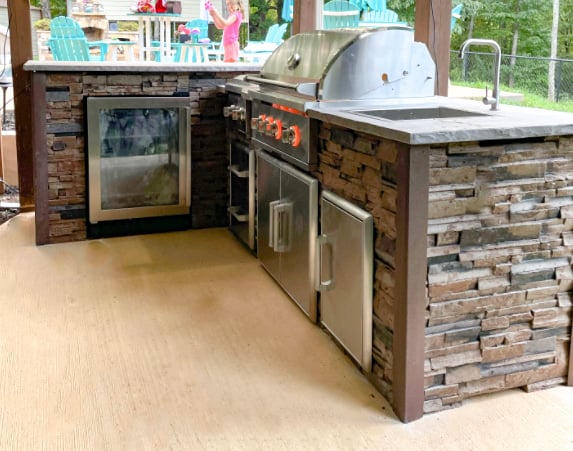 l shaped outdoor kitchen with wine cooler and storage and sink in stacked stone terra finish