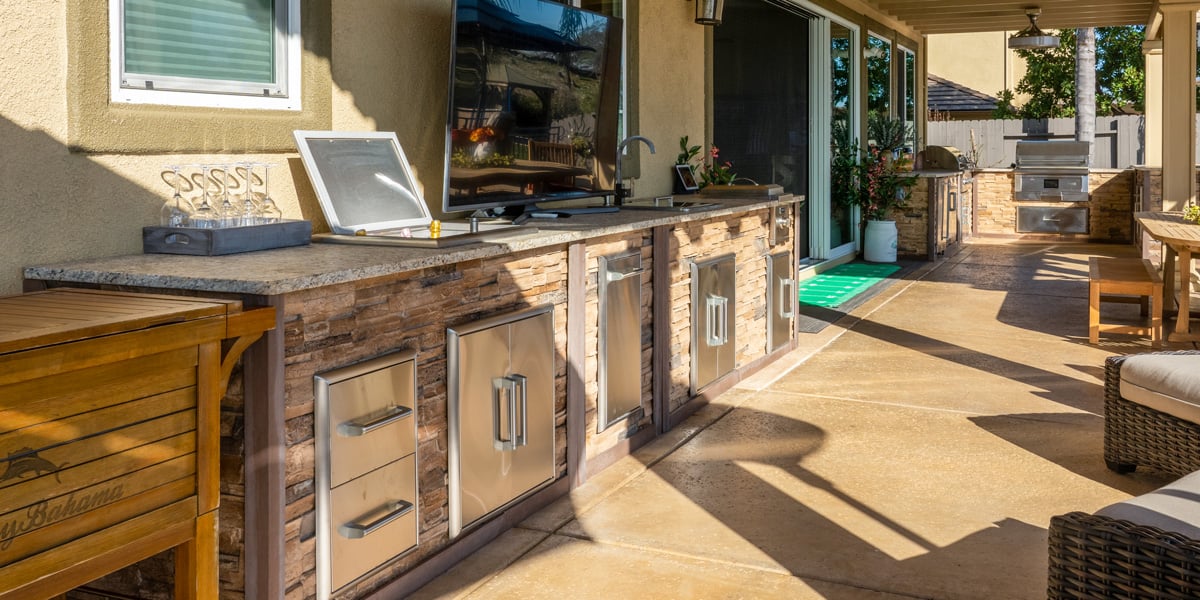large outdoor kitchen setup with drop in cooler and storage