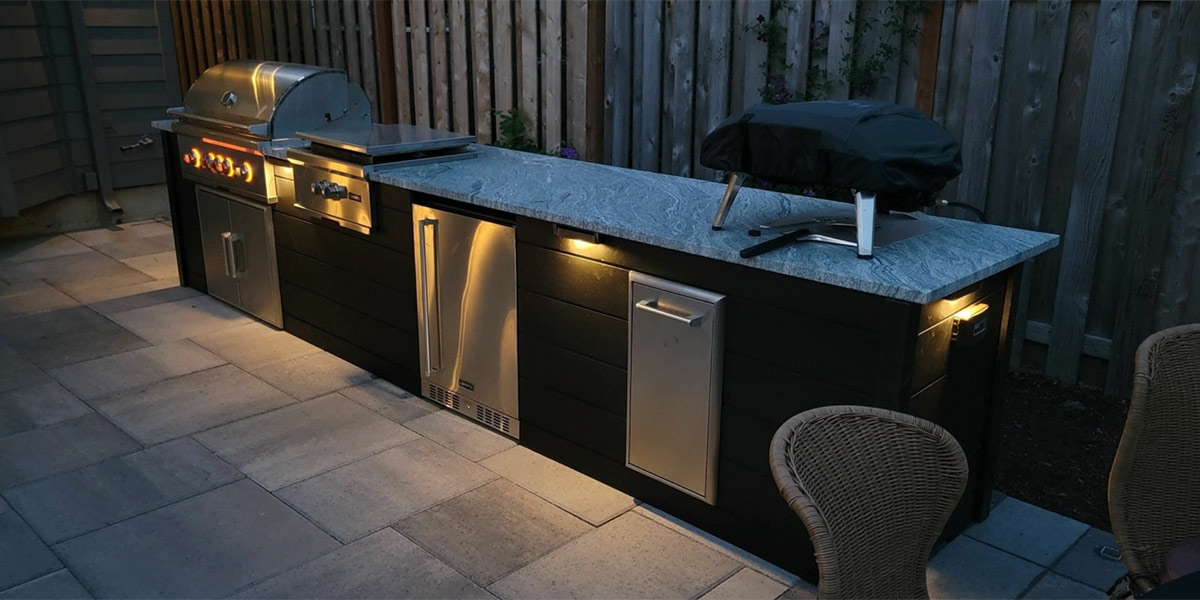 linear grill island in plank charcoal with pizza oven at night with lights