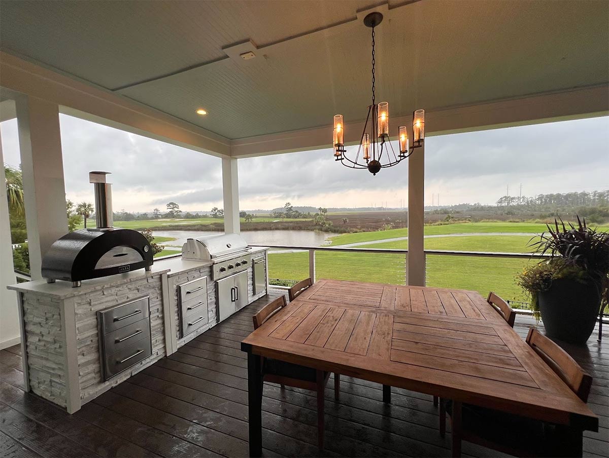 linear grill island with dining table under roof with chandelier lighting