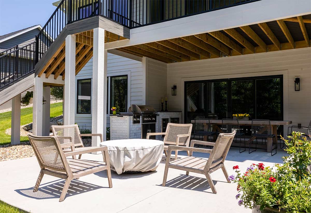 linear outdoor kitchen on patio with outdoor seating under a balcony