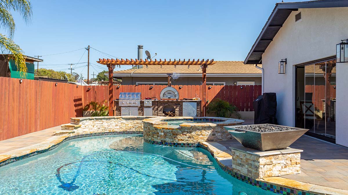 linear outdoor kitchen with pizza oven by a pool