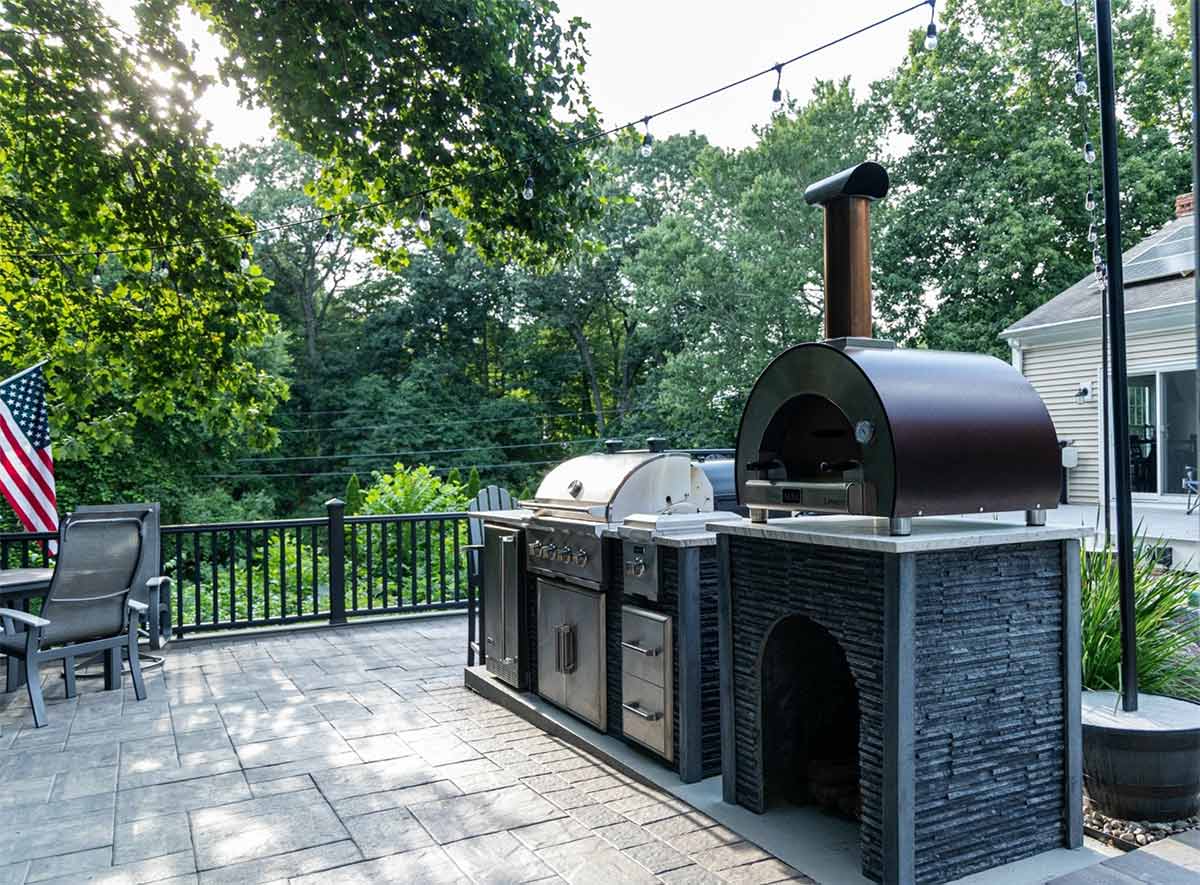 linear outdoor kitchen with pizza oven on paver patio