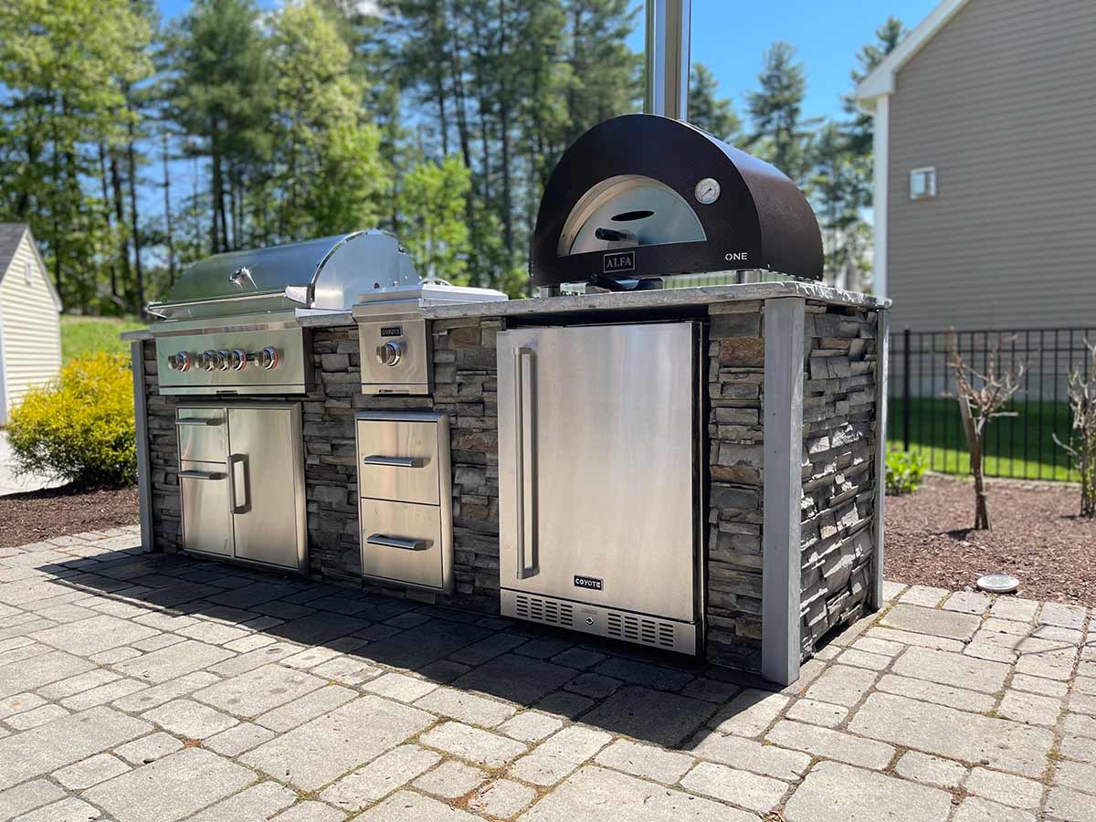 linear outdoor kitchen with side burner refrigerator and pizza oven